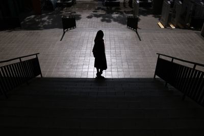 Rear view of woman walking on staircase in city