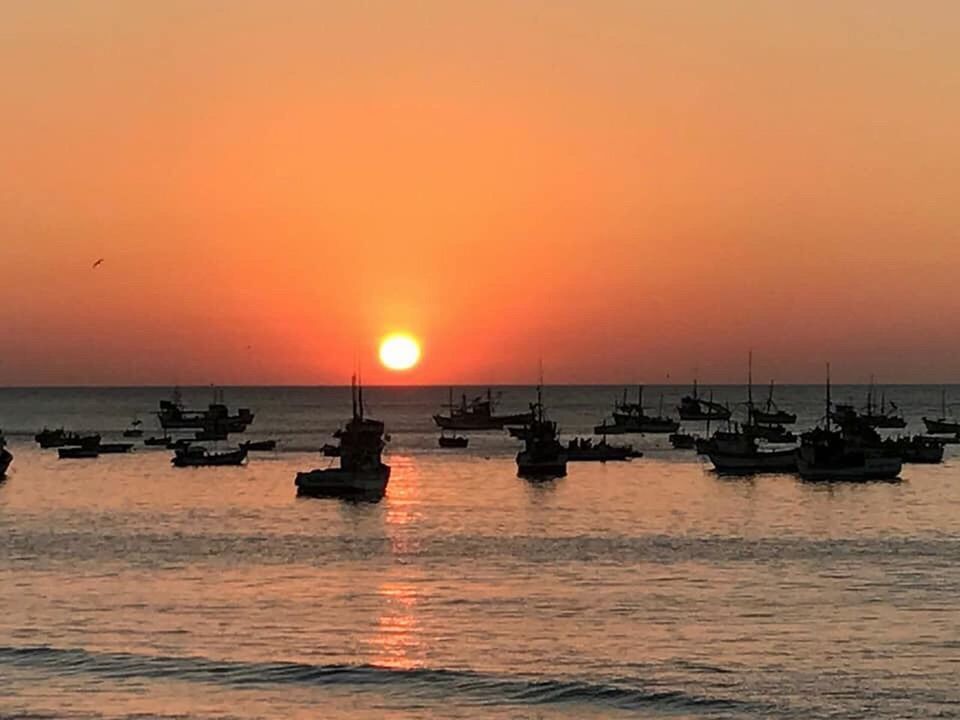 SILHOUETTE BOATS IN SEA AGAINST ORANGE SKY