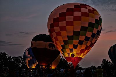 Low angle view of people by colorful hot air balloons against sky