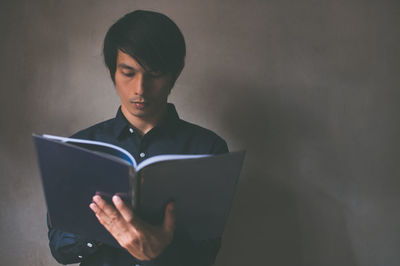 Young woman looking away while sitting on book