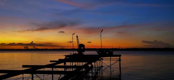 Silhouette pier over lake against sky during sunset