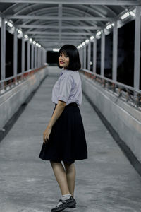 Full length portrait of woman standing on covered bridge