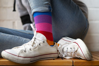 Woman sitting with her white sneakers and colored socks.
