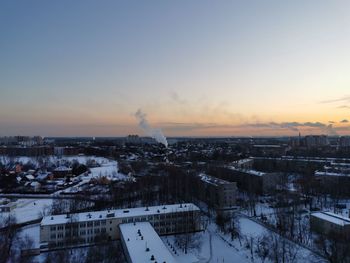 High angle view of snow covered buildings against sky during sunset