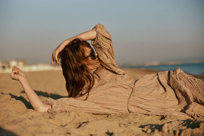 Rear view of woman standing at beach against sky