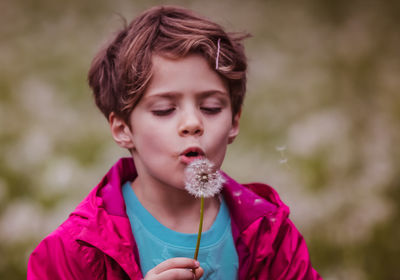 Cute boy blowing dandelion in park
