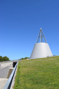 Built structure on field against clear blue sky