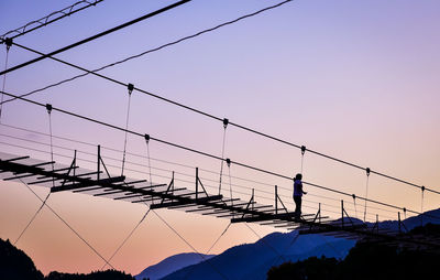 Silhouette electricity pylons against clear sky during sunset