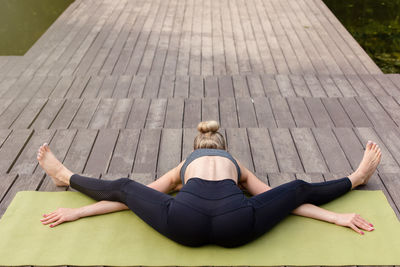 A beautiful blonde woman on a wooden platform on mat , does yoga and stretching