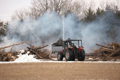 Tractor moves brush during a controlled burn on a farm property to create more arable land