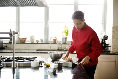 Woman using tablet computer on kitchen counter while preparing food