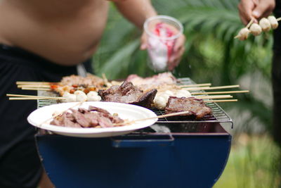 Close-up of person preparing food on barbecue grill