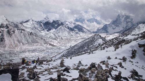 Scenic view of snow covered mountains against cloudy sky