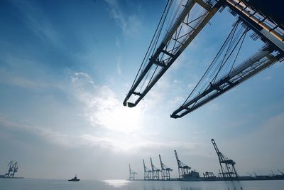 Cranes at commercial dock against sky