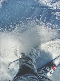 Low section of person skiing on snow covered field