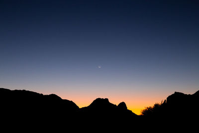 Silhouette mountains against clear sky at sunset