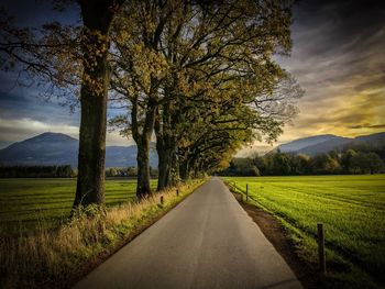 Road amidst field against sky