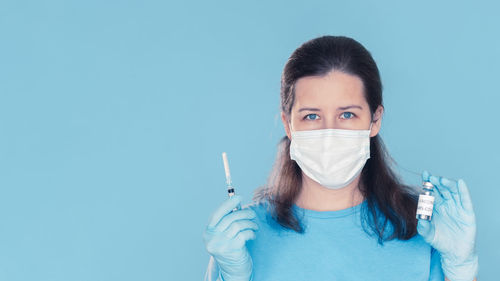 Portrait of young woman against blue background