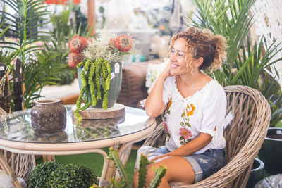 Woman smiling while sitting on potted plant