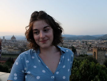 Close-up of smiling woman standing against cityscape