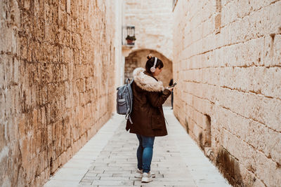Full length rear view of woman walking on wall