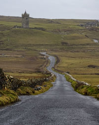 Road amidst field against sky