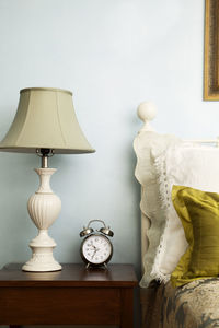 Alarm clock and lamp on side table in bedroom