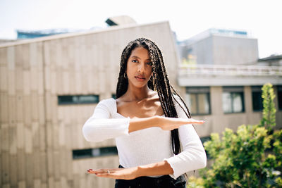 Portrait of young woman standing against building