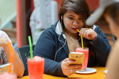 Young woman using mobile phone while sitting in laptop