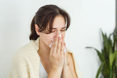 Close-up of young woman with eyes closed against white background