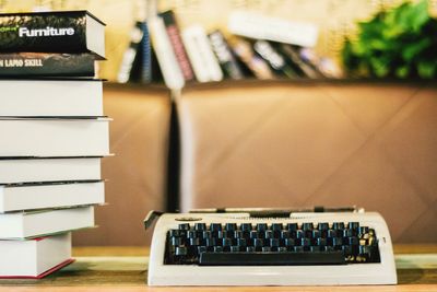 Typewriter by stack on books at table