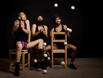 Young jugglers sitting on chairs with balls on stage