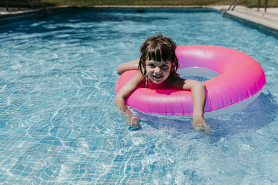 Portrait of smiling girl with inflatable ring in swimming pool