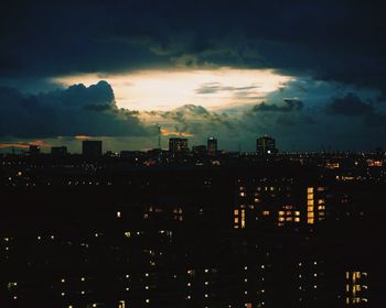 Illuminated cityscape against cloudy sky