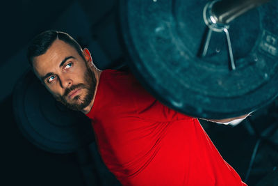 Male athlete exercising with barbell in gym