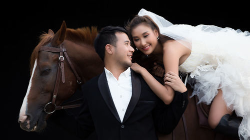 Young couple standing against black background