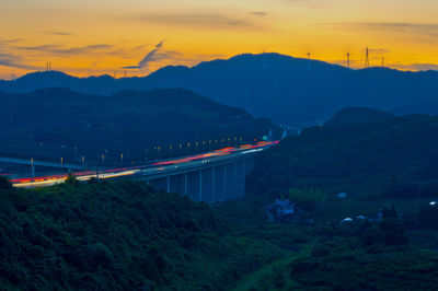 Bridge over mountains against sky during sunset