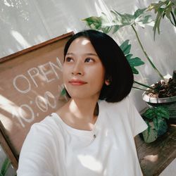 Portrait of young woman standing against plants