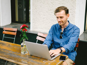 Young man using mobile phone while sitting on table