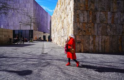 Rear view of woman walking on footpath in city