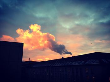 Low angle view of silhouette factory against sky during sunset