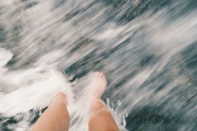 Low section of man splashing water in sea