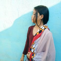 Young woman standing against wall