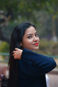 Portrait of young woman wearing red lipstick at park