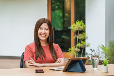 Portrait of smiling young woman using laptop on table