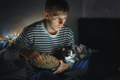 Man watching movie with cat at home