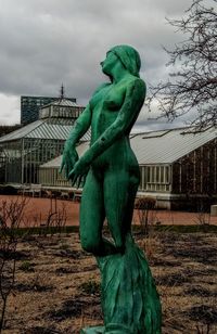 Statue of bare tree against cloudy sky