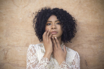 Portrait of young woman looking away against wall