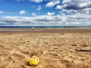 Scenic view of beach against cloudy sky