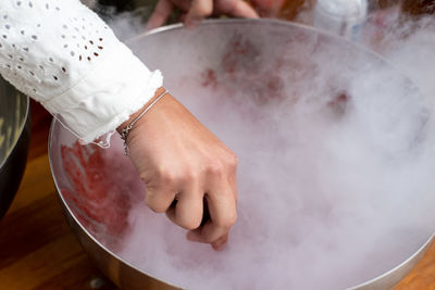 Midsection of woman holding ice cream on table